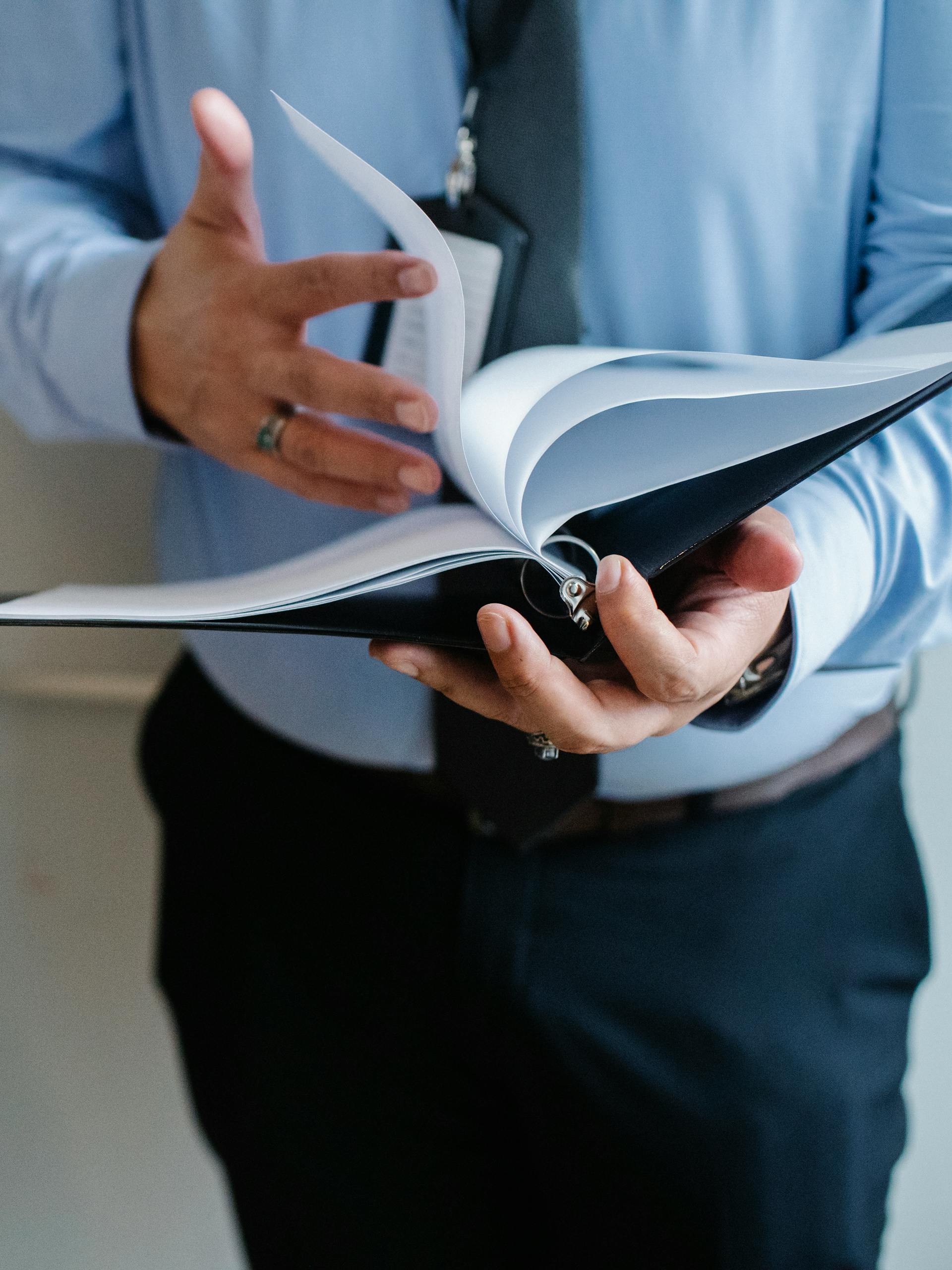 A business professional in a suit flips through documents indoors, emphasizing formal work settings.